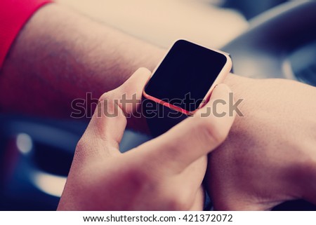 Hands of african male model using trendy smart wrist watches in a car. Popular new technology to always stay connected to internet and social media. Close up macro 