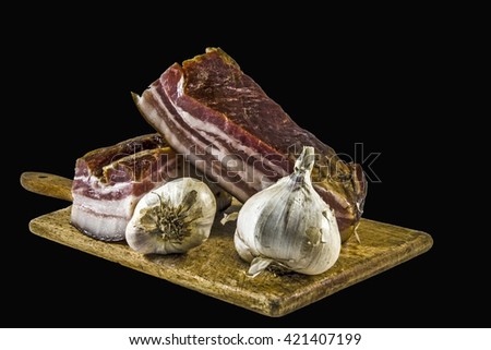 Domestic bacon and garlic on wooden kitchen board.                              