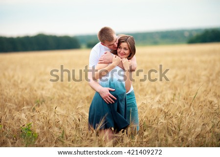 Outdoor portrait of young pregnant couple in field