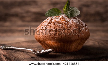 Tasty muffin with cherry and mint on vintage wooden background