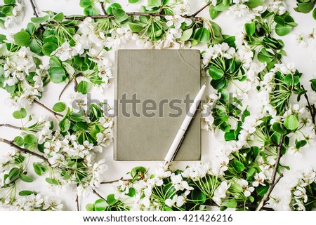 Old book, pen and branches with leaves and flowers on white background. Flat lay composition