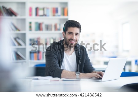 student preparing exam and learning lessons in school library, making research on laptop and browse internet Royalty-Free Stock Photo #421436542