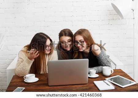 Three girls work and coffee with laptop. Young girls friends happy with computer. Discussion, startup, friendly conversation. Women friendship, modern life, gossip and internet dating concept. 