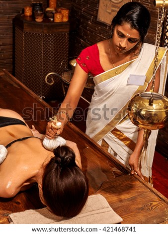 Woman having ayurvedic massage with pouch of rice. Exotic India massage.