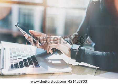 Photo Woman Working Modern loft,Wearing Generic Design Smart Watch.Female Hands Touching screen Mobile Phone.Manager Work Process.Laptop on the wood Table.Horizontal,Burred background. Film effects.