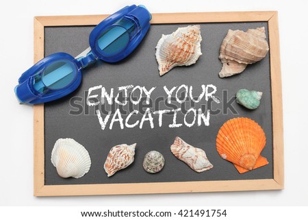 Enjoy Your Vacation text on chalk board with swimming goggle and shell - vacation and business concept