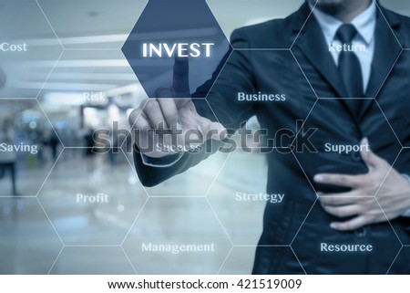 Businessman touching the Invest icon with business success virtual screen on the Abstract blurred photo of store in department store bokeh background, Business technology concept 