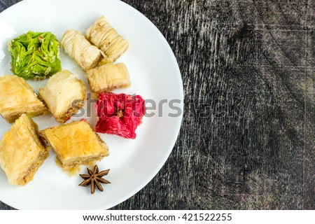 Turkish and Arabic Traditional Dessert baklava on white plate on grunge wooden background. Royalty-Free Stock Photo #421522255