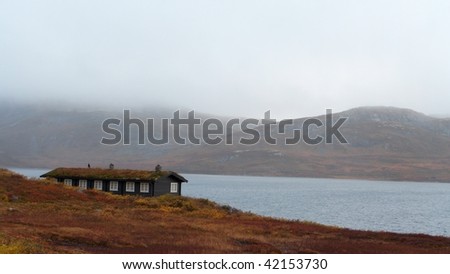 traditional norwegian wooden houses standing on a lake coast and mountains in the background
