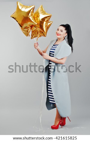 Young smiled woman with gold balloons at hands background gray isolated