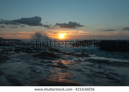 Sunset and blue hour over natural rock with strong wave at Muriwai Beach, Auckland, New Zealand
