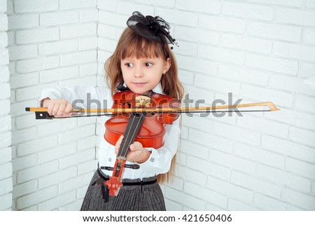 little girl playing the violin and looking away