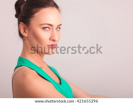 closeup portrait of a beautiful serious woman in green undershirt looking at hte camera