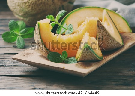 Fresh sweet orange melon on the wooden table, selective focus and toned image Royalty-Free Stock Photo #421664449