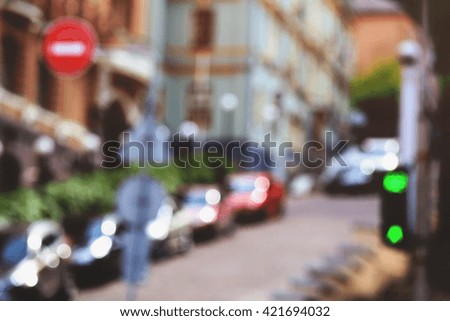 Traffic street in european city in bokeh. Defocused city street background. Blurred stylish urban  background. Toned photo. Row of cars along the street