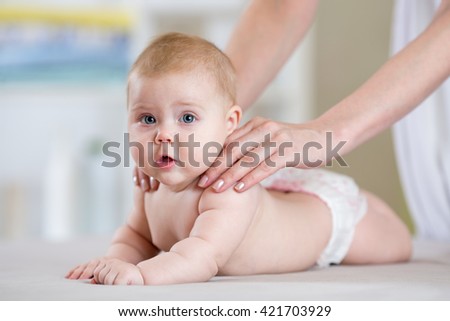 Mother massaging baby in the bed at home