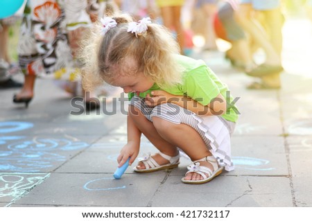 little girl draws a chalk on asphalt
