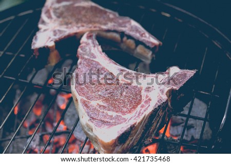 Two ribeye beef steaks on the charcoal grill. Toned picture