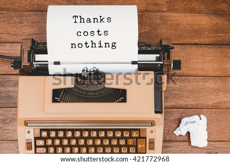 Thanks costs nothing message on a white background against view of an old typewriter and paper