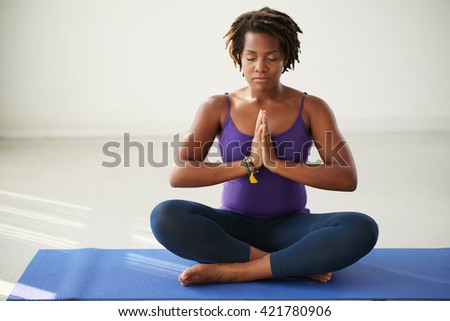 African-American woman meditating in lotus position Royalty-Free Stock Photo #421780906