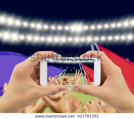 Man photographing his team's victory with a smartphone of the football stadium