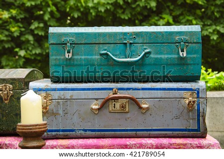 Set of old colorful metallic suitcases. Rural vacation concept. Vintage background.