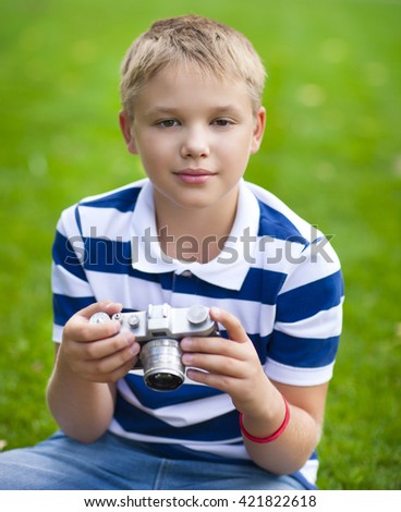 Happy smiling little boy with retro vintage camera in summer park
