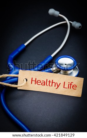 Healthy  life word in paper tag with stethoscope on black background - health concept. Medical conceptual