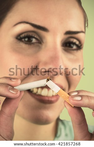 Close-up portrait of happy woman holding cigarette against green background