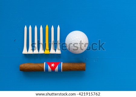 Detail of luxury Cuban cigars and golf equipments on the blue wooden desk