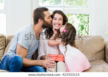 Happy mother receiving a gift from her husband and daughter in living room