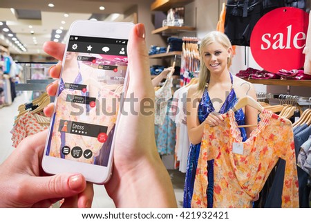 Hand holding smartphone against woman holding up orange shirt