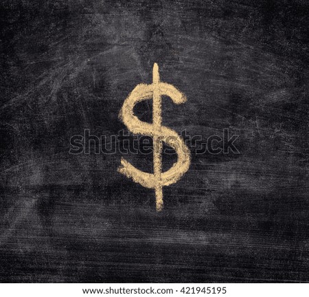 Drawn dollar sign on black chalkboard background. Close up.