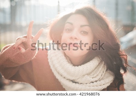 Portrait of young woman making peace sign in park