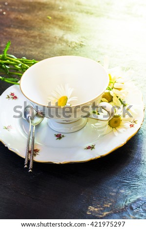 Rusric table setting with vintage silverware and plates and wild daisy flowers on vintage wooden table
