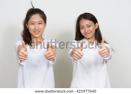 Two Asian girls giving thumbs up