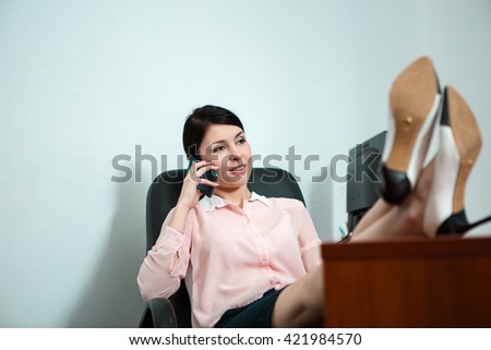 Relaxed business woman sitting in a chair with legs over the table.