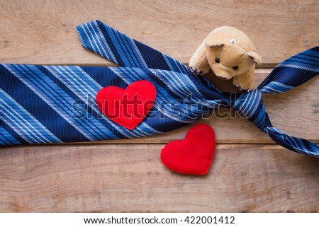 Father's day background with blue necktie, brown teddy bear and red heart on rustic wooden background