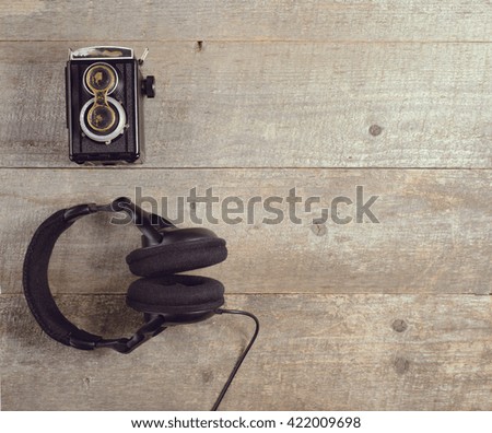 Old vintage camera and modern headphones on wooden table. top view. copy space.