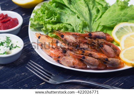 Fried shrimp with lemon & salad on wooden background