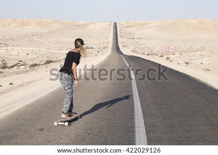 Skater woman at the long road. Western Sahara.