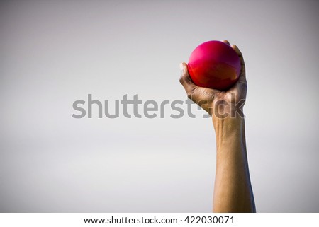 Hand holding a red ball against grey background