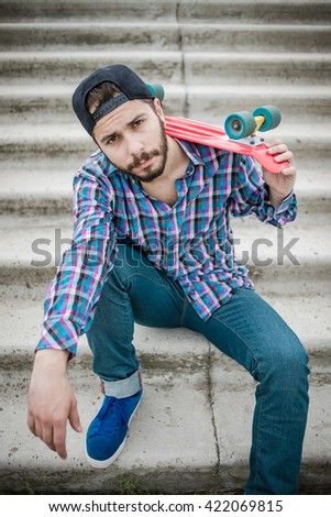 Stylish young guy on a red skateboard