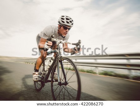 Cyclist pedaling on a racing bike outdoors in a sunny day Royalty-Free Stock Photo #422086270