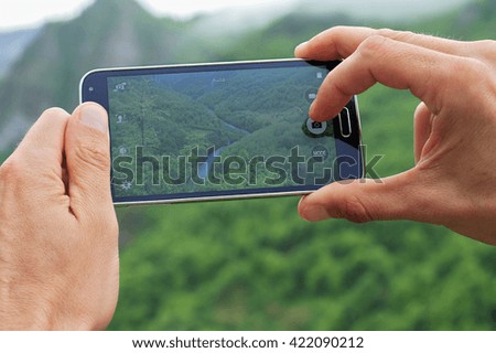 Man taking photo of mountain river canyon with mobile cell phone. Active holiday vacation, travel concept