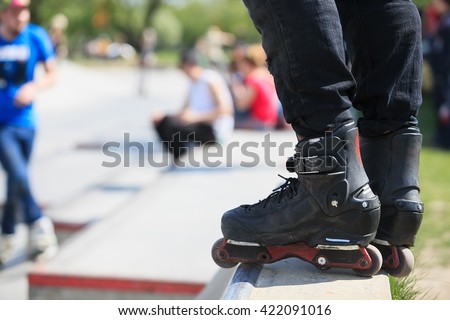 Feet of roller blader wearing aggressive inline skates on top of concrete ramp in outdoor skatepark.Extreme sports athlete in skating park