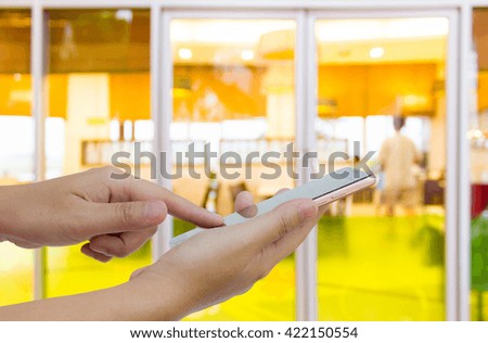 Girl use mobile phone, blur image of coffee shop as background.