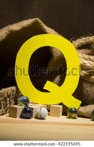 The letter " Q " by  Photo font " Yellow Texture " and subjects with active texture. Wood, burlap, glass beads. Preparation for graphic design