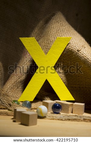 The letter " X " by  Photo font " Yellow Texture " and subjects with active texture. Wood, burlap, glass beads. Preparation for graphic design