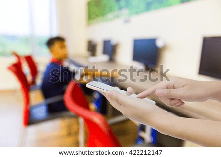 Girl use mobile phone ,blur image of boy playing computer game as background.